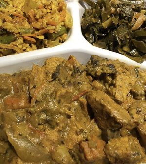 Curry chickun with side of greens and fried rice  at The Land of Kush in Baltimore