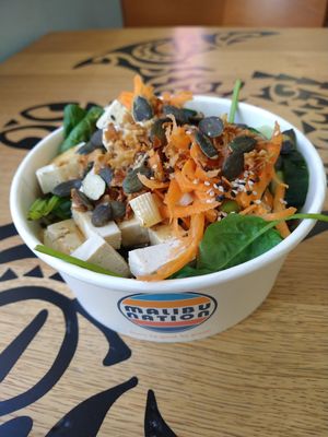 Bowl met rijst, spinazie, tofu, wortel, komkommer, edamame, pompoenpitten, sesamzaad en gebakken uitjes at Malibu Nation in Basel