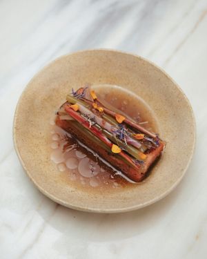 pickled and raw stems · red lentils ‘tofu’ · homemade dashi · globe amaranth infused oil · herbs · flowers at Venn Canteen in Porto