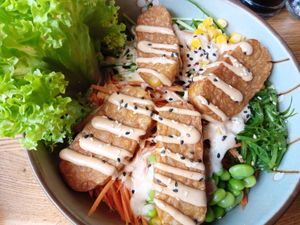 Bowl with tempeh, edamame, wakame, corn, carrots, cucumber, avocado, salad, cocktail sauce at Udum in Cologne