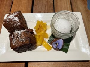 Slightly crisp crusty banana cake in cream, caramelized pineapple, a superrich little chocolate ganache bomb with edible purple flower, and macadamia ice cream  at Beach House by Roy Yamaguchi in Kahuku