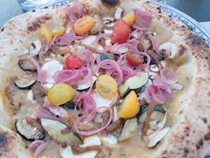 Vegana summer love with a sauce from yellow tomatoes, rosemary marinated courgette, mushrooms, red pesto, pickled red onion and fresh tomatoes at 180g Pizza in Nantes