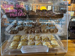 Case featuring pastries. GF blue berry muffins, brownies, Vegan and gluten free Almond joy doughnuts, vegan and GF orange cinnamon doughnuts, and vegan peach pop tarts  at Raven's Nest Coffee House in Culpeper
