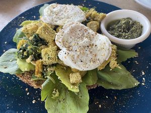 Avocado toast with poached eggs on the top and homemade pesto on the side  at The Breakfast Cafe in Dahab