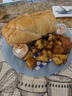 Crab cake poboy with side of potatoes at Meals From The Heart Cafe in New Orleans
