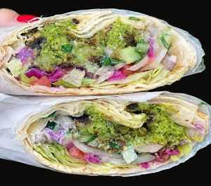 Crispy hot falafel, surrounded by cool and crunchy diced tomatoes, cucumbers, and onions, and drenched with tahini sauce. wrapped in a warm pita bread. Served with Tahini sauce. at Habibi Kush in Miami