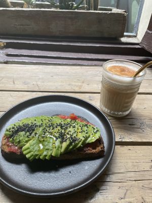 Tostada con tomate, aguacate, sésamo y AOVE + iced chai latte con leche de avena  at Slow Café in Madrid