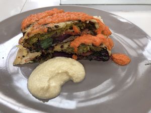 Olive falafel Piadina with tomato sauce on top and hummus beside  at Green Falafel - Mercado San Blas in Cusco