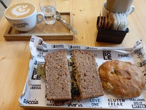 Segalone sandwich, focaccina with olives, and a cappuccino with oat milk at Forno Brisa Lab in Bologna
