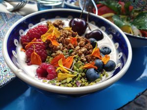 Amandelyoghurt met granola, pistache, vers fruit en eetbare bloemen at DAR Restaurant & Cocktail Bar in Zurich