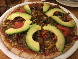 Vibrant vegan pizza. Made with whole-wheat flour, tomatoes, avocados, Kalamata olives, garlic and a variety of vegetables.  at Avocado in Athens
