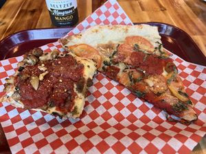 Detroit-style slice with vegan sausage, vegan cheese, and garlic and a New York-style Margherita slice  at TNT Pizza in San Diego