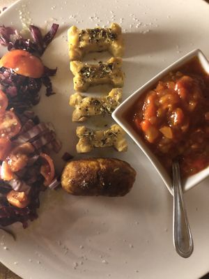 Bone-shaped tempeh, potato croquette, spicy salsa, red cabbage and tomato salad at Elena Carmilla  in Rivarossa