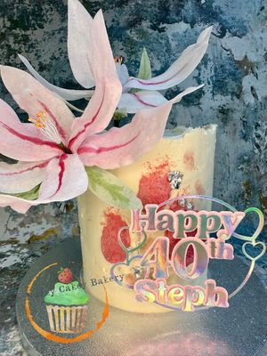 Gluten-free/Vegan chocolate sponge, textured buttercream with smudges of pink and  handmade wafted paper lily’s at The Nakey Cakey Bakery in Castletown