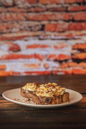 Cajeta con Queso Holandés - Cajeta artesanal y queso holandés derretido sobre una rebanada de pan de caja orgánico. Coronado con plátano, nuez en trozos y queso holandes rallad at Molletería Central in Valle De Bravo