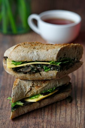 Vegan grilled mushroom baguette. Slices of vegan cheese on multi grain freshly baked baguette with grilled mushrooms and spinach. at Nama Café and Cake House in South East London