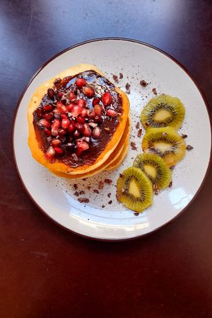Pancakes w/ date, hazelnut and cocoa cream + pomegranade + kiwi + cocoa nibs at Comércio Café Coworking in Porto