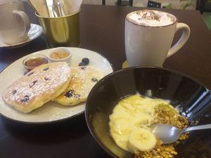Blueberry pancakes, yogurt with granola and hot chocolate at Comércio Café Coworking in Porto