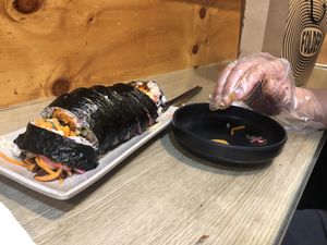 Giant spicy tofu kimbap eaten with gloved hand.   at Gimmyeonjang in Busan