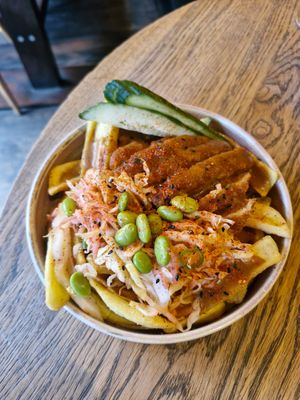 vegan chicken katsu loaded fries: crispy vegan chicken tenders, cucumber, ginger & sesame shredded cabbage, edamame & katsu sauce on canoe cut fries at Wolf at the Door in Manchester