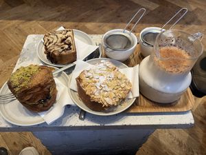 Left to right - Double baked pistachio and blueberry cruffin, chocolate & hazelnut cake and almond custard tart, plus chai latte with oat mylk   at Saint-Jean in Amsterdam
