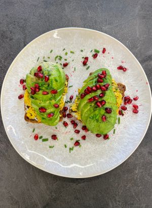 Vegan avocado toast with tofu scramble, pomegranate a black salt on organic rye bread or gluten free bread at Mamafood in Prague