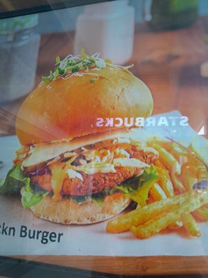 Fraudulent photo of the so called chicken burger they have hanging in their window. Starbucks is across the way so reflecting in the window at The Vegan Chef - Sandton in Johannesburg