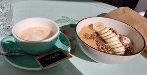 Bowl with soy yogurt, banana and lots of peanut butter😄 Oat cappuccino on the side at Hygge in Lisbon