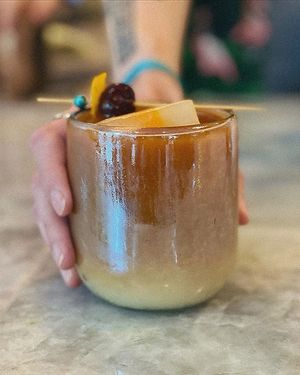 Single Origin Cold brew with Vermont Maple Syrup, Oat Milk, Orange Bitters, topped with express orange peel and a maraschino cherry. Served with an orange infused rock of ice.  at Paradeco Coffee Roasters in St Petersburg