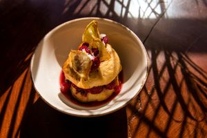 Baked sourdough fritters made with homemade almond milk and spices, accompanied by our own version of “api” made of quinoa and hibiscus flower, fresh fruits and coconut chips. at Biofilia - Botánica Coffee House in La Paz