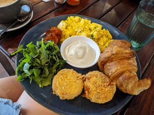 The Amelie - Herbert & cheezy tofu scramble, warm croissant, balsamic tomatoes, 2 hash browns, & confit garlic aioli. #Veganuary at Cinnamon & Co in West End