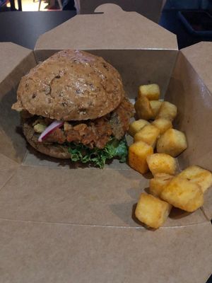 Crispy fried chyken tossed in Buffalo sauce, with coconut bacon, crushed pickle chips, Caesar dressing, sliced tomato, and crisp lettuce on a multigrain bun. 
And the polenta tots? at Beaucoup Plant Based in Sudbury