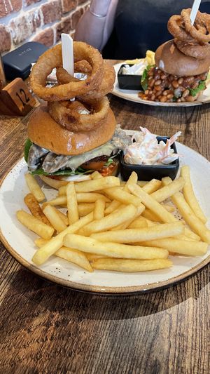 Two stacked burgers with fries, onion rings and coleslaw .  at Huggers in Norwich