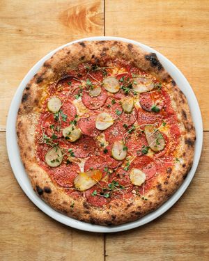 Best seller - plant based sausage pizza with pickles and greens.  at ČAU in Riga