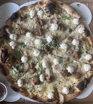 Vegan Bianca pizza with vegan cheeses, shallots, vegan sausage and vegan hot honey drizzle on the side 🍕  at Peels On Wheels in Rochester