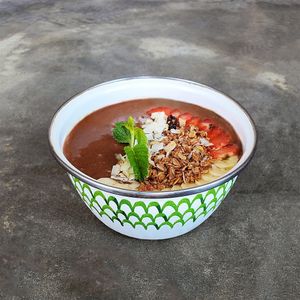 
Chocolate Maca Butter Smoothie Bowl (GFO): maca powder, cocoa, peanut butter, banana, almond milk, topped with granola, strawberry, banana, and coconut flakes at Warung Dua Hati in Canggu