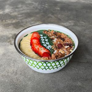 Superfood Spirulina Smoothie Bowl (GFO): green spirulina, protein powder, banana, cucumber, kale, spinach, berries, soy milk, topped with granola, strawberry, and banana at Warung Dua Hati in Canggu