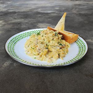Angel Hair Creamy Mushroom: creamy carbonara-style pasta with vegan chicken, mushrooms, onion, parsley, topped with cashew parmesan cheese, served with garlic bread slices at Warung Dua Hati in Canggu