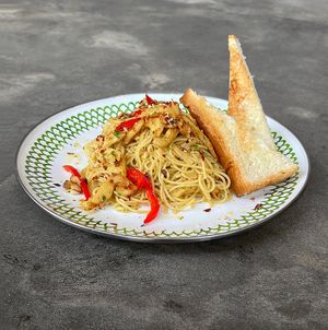 Angel Hair Aglio Olio: olive oil and garlic pasta with vegan chicken, cashew parmesan cheese, bell pepper, onion, parsley, served with garlic bread slices at Warung Dua Hati in Canggu