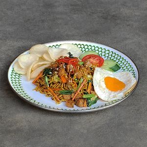Special Fried Noodles / Mie Goreng Spesial: wok-fried noodles with vegan protein, veggies, topped with a sunny side up "egg" and crackers at Warung Dua Hati in Canggu