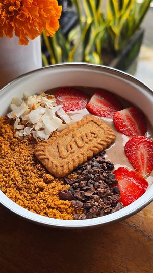 Lotus Biscoff Smoothie Bowl: a creamy blend of Lotus Biscoff spread, banana, cocoa, and oat milk, strawberries, crunchy Biscoff crumbs, cocoa nibs, coconut flakes, Biscoff biscuit at Warung Dua Hati in Canggu