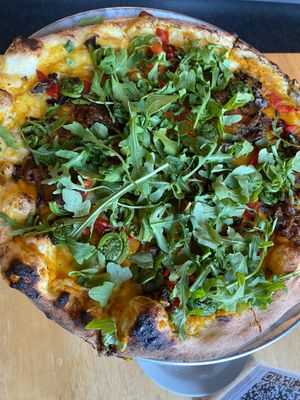 Custom pizza with butternut squash sauce abounds with fiddleheads and fresh arugula at Cushnoc Brewing Co in Augusta