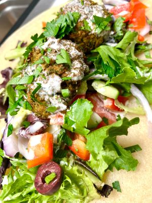 Falafel wrap. Gluten free house made falafel, Kalamata olives, tomato, red bell pepper, cucumber, feta, house made hummus and tahini dressing, green leaves and cassava wrap  at Botanika Cafe in Ridgefield