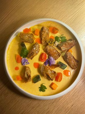 Artichoke Tiradito - Artichoke confit with yellow chilli and almond emulsion. With cherry tomatoes, sweet potato, baked avocado, lime chilli and hot paprika oil. at MUDRA Plant Based  in Madrid