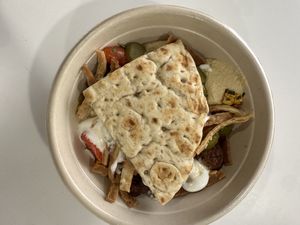 Bowl with white rice, hummus, falafel, corn, tomato and onion, pickles, pita chips, garlic dressing, tahini Caesar dressing, free pita  at CAVA in Melville