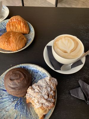 Apple strudel, pain au chocolate, some chocolate thing, croissant filled with vanilla custard and oat latte.   at Foxy's Bake Shop in Riga