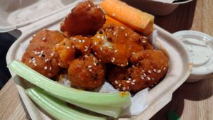 Buffalo cauliflower wings with side ranch. More wings w different sauce underneath paper. at elephant + vine  in Evanston