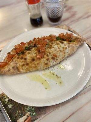 Mittagsmenü, Pizza nach Wahl Pizza Principessa, gefüllt mit Grillgemüse und veganem Käse. Oben drauf Tomatenwürfel mit Zwiebeln, Basilikum und Olivenöl.  at Uno e più in Kriens