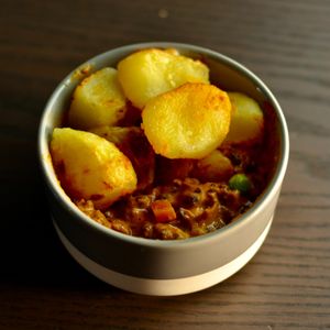 Dal Shepherds Pie - shepherds Pie with a spicy Indian twist! Beautifully slow cooked black dal with carrots, peas and spices, topped with crispy smashed roast potatoes. at Homegrown in Urmston