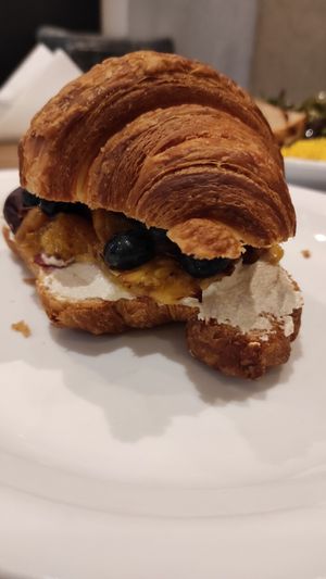 Croissant with almond cottage cheese blueberries and peach at Karma Organic Coffee in Krakow